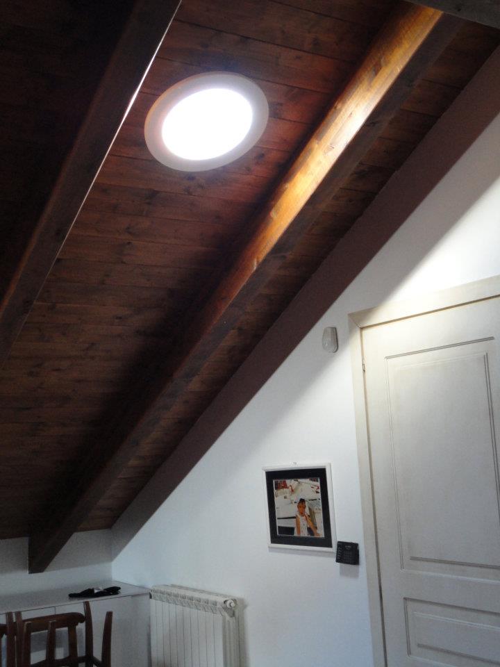 Intura SunTube-plafonddiffuser brengt daglicht in een ruimte onder een hellend houten dak